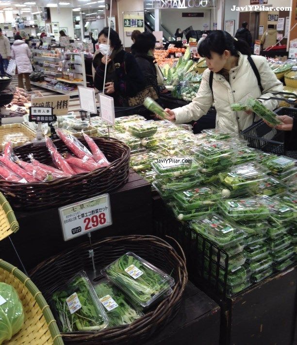 Mujer comprando un paquete de siete hierbas para nanakusagayu (七草粥) el 6 de enero en un supermercado de Kobe (Japón)