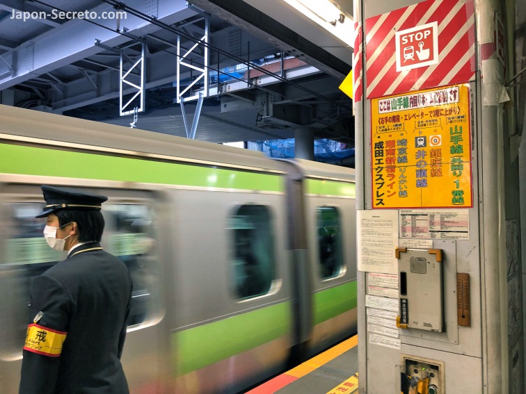 Tren de la línea Yamanote pasando por un andén de estación en Tokio y jefe de estación