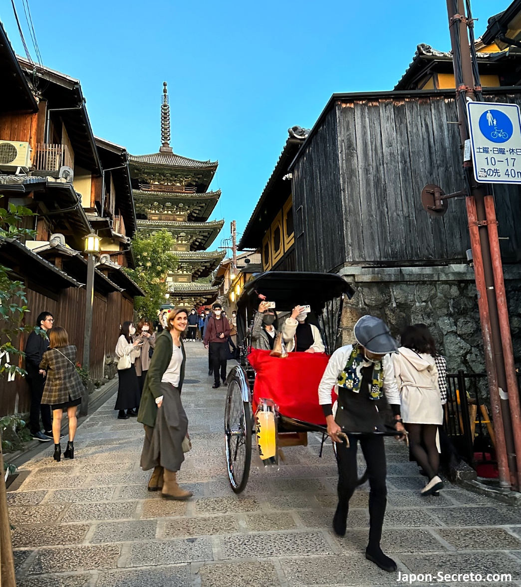 Jinrikisha (rickshaw) bajando por una callejuela del barrio de Higashiyama (Kioto) con la pagoda Yasaka al fondo