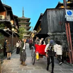 Jinrikisha (rickshaw) bajando por una callejuela del barrio de Higashiyama (Kioto) con la pagoda Yasaka al fondo
