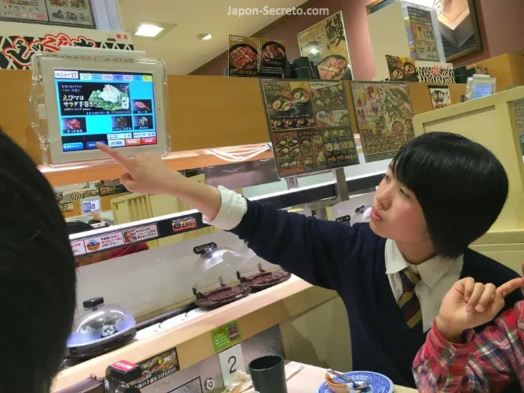 Eligiendo sushi y otros platos en un restaurante Kura Sushi (くら寿司) de Kioto cenando con amigos