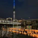Imagen del festival Asakusa Tōrō Nagashi (浅草とうろう流し) de farolillos flotando en el río Sumida, con la torre Tokyo SkyTree al fondo